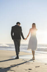 Couple holding hands while walking on beach - AFVF09145