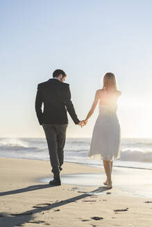 Paar hält sich beim Strandspaziergang an den Händen - AFVF09145