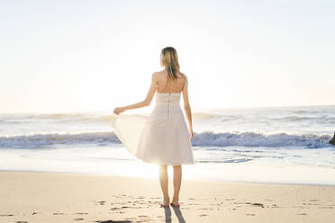 Junge Braut im Hochzeitskleid am Strand stehend - AFVF09147