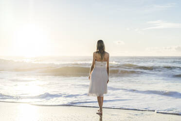 Braut mit Blick auf Sonnenaufgang Blick, während stehend am Strand - AFVF09149