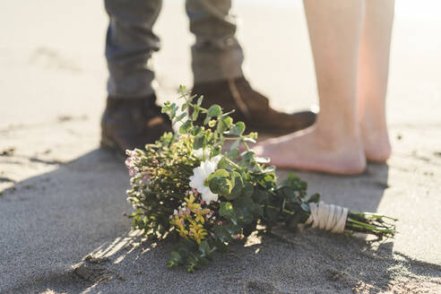 Blumenstrauß am Strand mit stehendem Paar im Hintergrund - AFVF09155