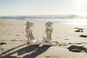 Ein Paar Sandalen am Strand bei Sonnenaufgang - AFVF09157