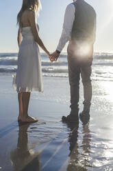 Junges Paar hält sich am Strand die Hände - AFVF09160