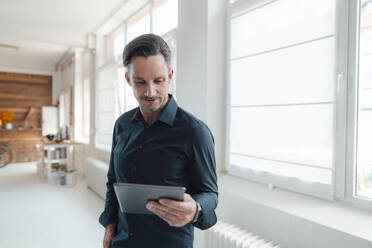 Reifer männlicher Profi, der im Büro an einem digitalen Tablet arbeitet - JOSEF05511