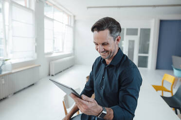 Smiling male professional working on digital tablet in office - JOSEF05535