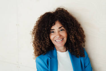 Businesswoman with curly hair smiling in office - JOSEF05558