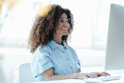 Smiling businesswoman wearing eyeglasses working in office - JOSEF05616