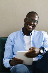 Glücklicher Mann mit Brille und digitalem Tablet zu Hause - GIOF13388