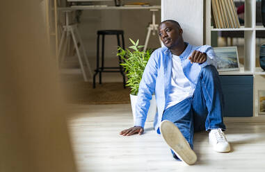 Thoughtful man sitting in front of wall at home - GIOF13397