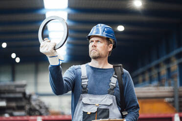 Male engineer checking circle shape equipment in factory - JOSEF05648