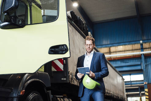 Männlicher Manager, der ein digitales Tablet benutzt, während er neben einem Lastwagen steht - JOSEF05657