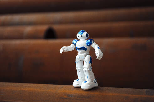 Robot toy on rusted pipe in warehouse - JOSEF05674