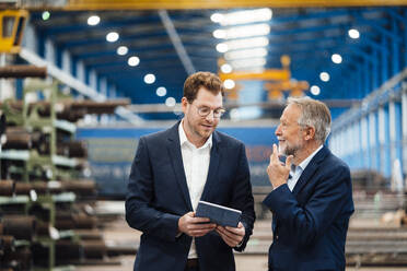 Männliche Manager bei einer Diskussion über ein digitales Tablet in einer Fabrik - JOSEF05736