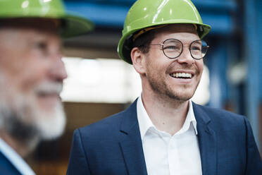 Happy businessman talking with coworker in factory - JOSEF05746