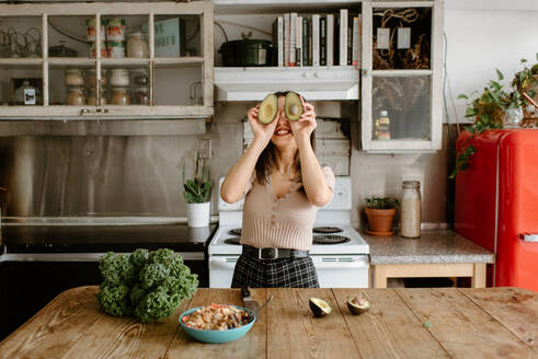 Smiling young woman holding avocado in front of face - ISF25083