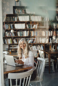 Female freelancer with laptop sitting in coffee shop - JOSEF05778