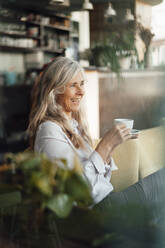 Fröhliche Geschäftsfrau, die in einem Café sitzt und Kaffee trinkt - JOSEF05779