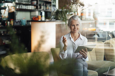 Freiberuflerin, die an einem Videoanruf über ein digitales Tablet im Café teilnimmt - JOSEF05784