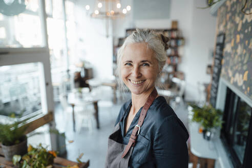 Lächelnde Unternehmerin mit Schürze in einem Cafe - JOSEF05802