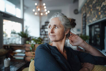 Nachdenkliche Frau mit grauem Haar sitzt auf einem Stuhl in einem Cafe - JOSEF05810