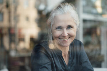 Smiling woman looking through cafe window - JOSEF05818