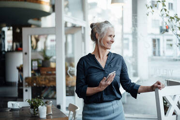 Geschäftsfrau mit Mobiltelefon am Tisch eines Cafés - JOSEF05819