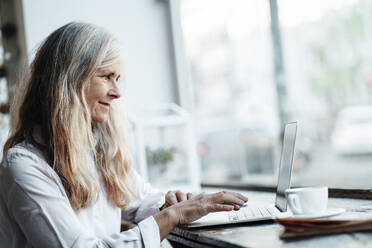 Female freelancer using laptop at table in cafe - JOSEF05834