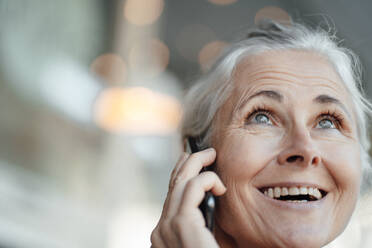 Cheerful businesswoman talking on mobile phone in cafe - JOSEF05868