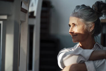 Smiling woman with gray hair bun in coffee shop - JOSEF05873