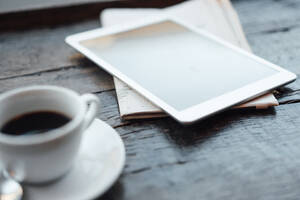 Digital tablet with coffee cup and newspaper on table in cafe - JOSEF05884