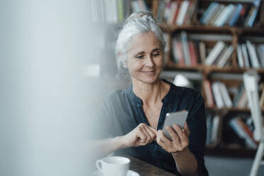 Female freelancer using smart phone in coffee shop - JOSEF05887