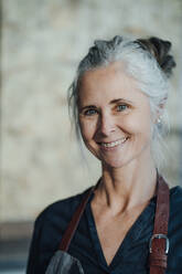 Smiling female cafe owner wearing apron in coffee shop - JOSEF05893