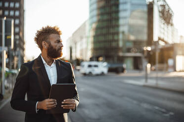 Mature businessman holding digital tablet on street - GUSF06353