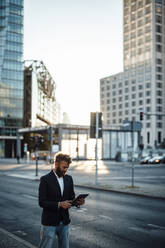 Businessman in smart casual using digital tablet on street - GUSF06355