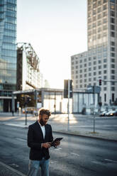 Geschäftsmann in eleganter Freizeitkleidung mit digitalem Tablet auf der Straße - GUSF06355