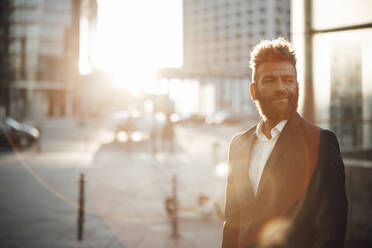 Männlicher Berufstätiger mit Bart, der an einem sonnigen Tag im Freien steht - GUSF06357