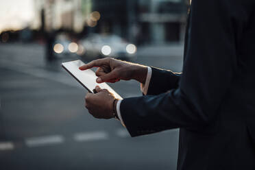 Male freelancer using digital tablet on street - GUSF06370