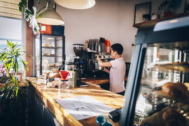 Weibliche Barista bei der Kaffeezubereitung in einem Cafe - OMIF00019