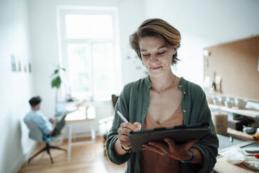 Smiling businesswoman using digital while working at home - GUSF06405