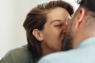 Woman with eyes closed kissing man at home - GUSF06444