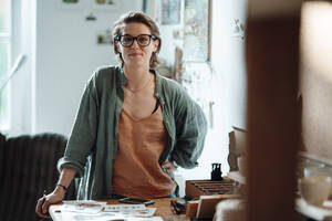 Female illustrator wearing eyeglasses at home office - GUSF06461