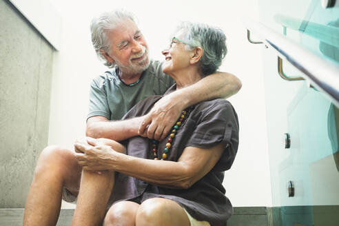 Älteres Paar, das sich auf einer Treppe sitzend umarmt - SIPF02351