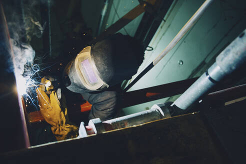 Junger männlicher Schweißer bei der Arbeit mit dem Schweißbrenner auf der Baustelle - MASF25174