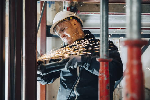 Männlicher Bauarbeiter beim Schneiden von Metall mit Maschinen auf der Baustelle - MASF25177