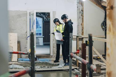 Weiblicher Ingenieur diskutiert mit männlichem Bauarbeiter auf der Baustelle - MASF25183