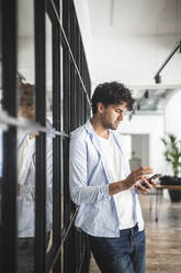 Young businessman using smart phone in office - MASF25193