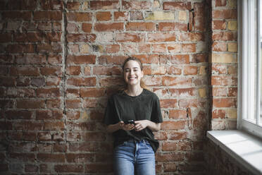 Lächelnder junger weiblicher Hacker mit Smartphone im Büro - MASF25223
