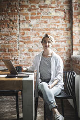 Portrait of female hacker sitting on chair in office - MASF25228