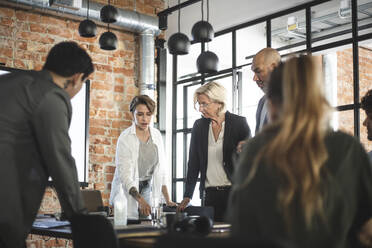 Male and female computer programmers discussing with investors in startup company - MASF25298