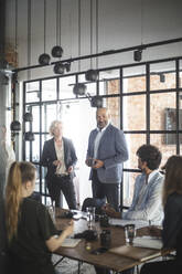 Male and female investors discussing with hackers during meeting at startup company - MASF25299